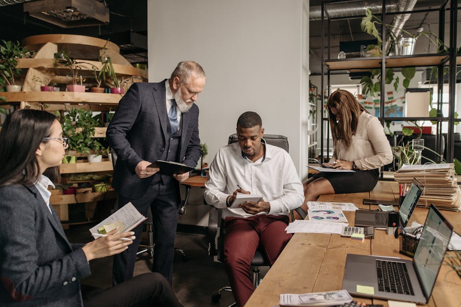A diverse group of coworkers meeting in a contemporary office, working together on projects with technology and documents.